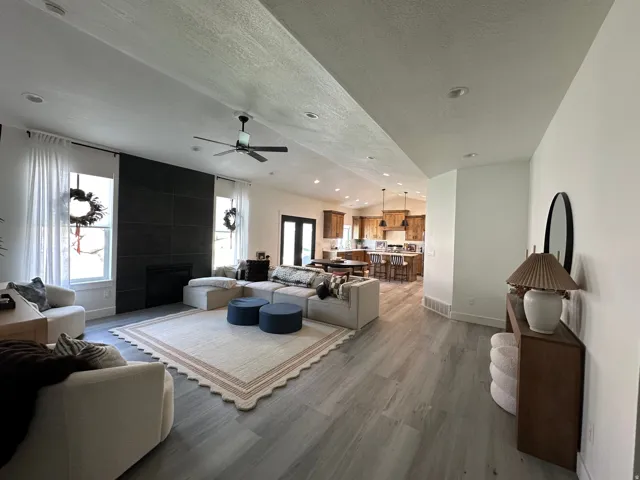 Spacious living area featuring wood-finish flooring, a contemporary fireplace with a dark tile surround, and recessed lighting