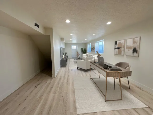 Recessed lighting illuminates the open-concept space featuring wood-finish flooring and light-toned walls