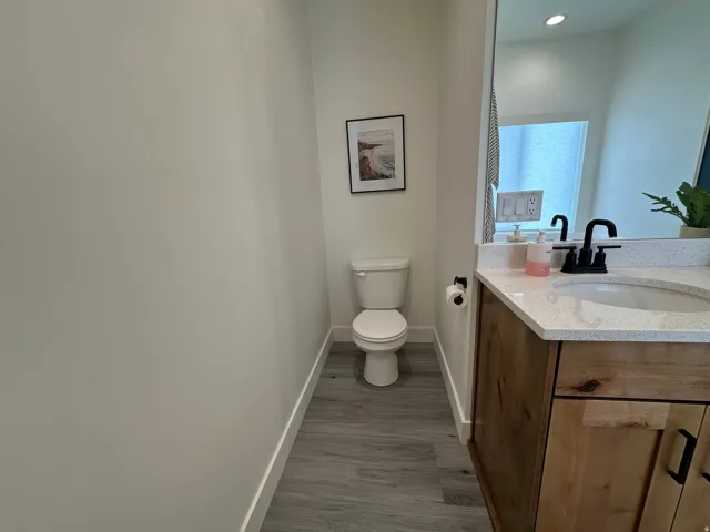 Wood-finish flooring, white walls, and a wood vanity with a white countertop