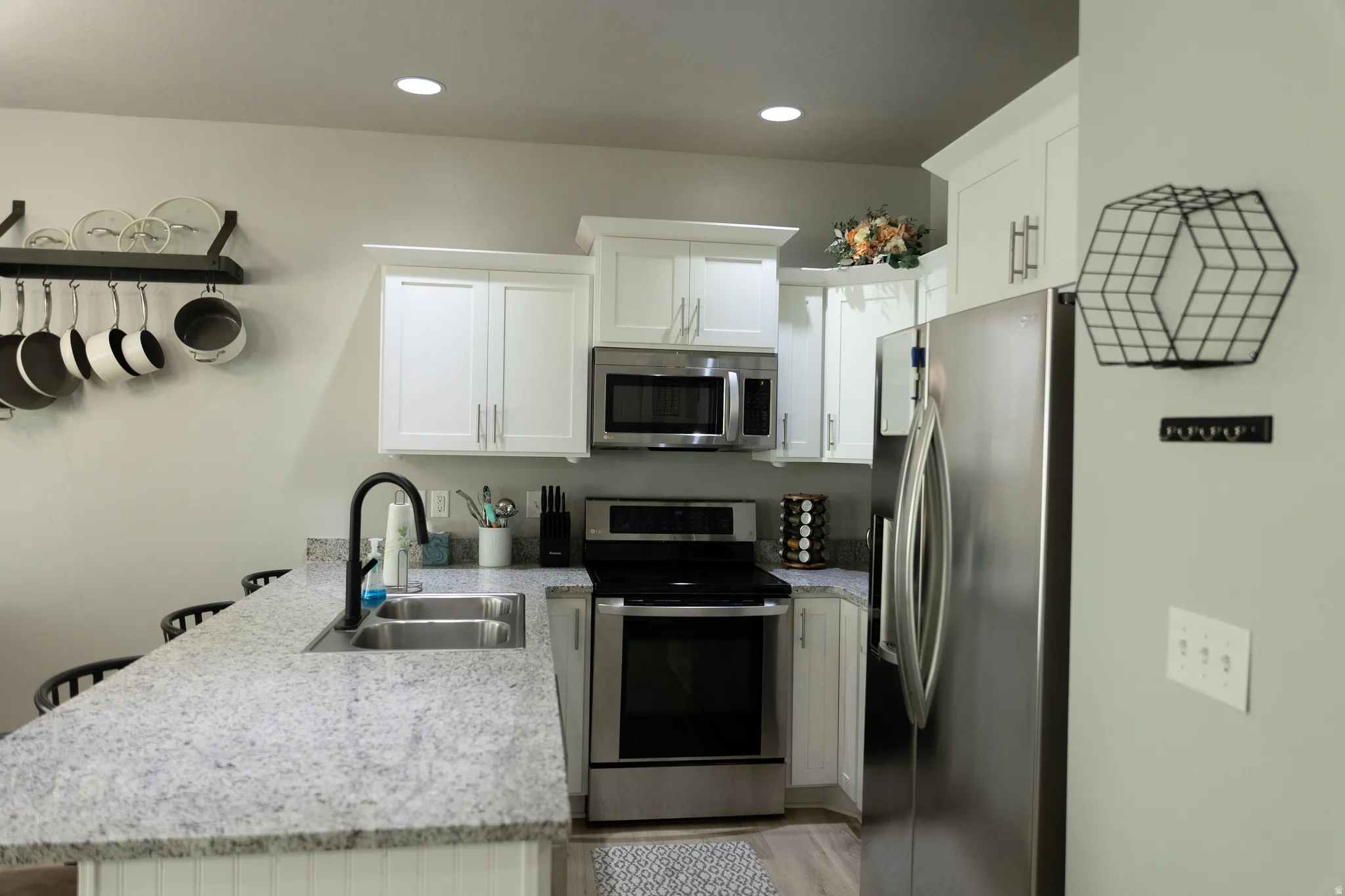 Kitchen featuring white cabinetry, stainless steel appliances, a double basin sink with a black faucet, recessed lighting, and a speckled countertop