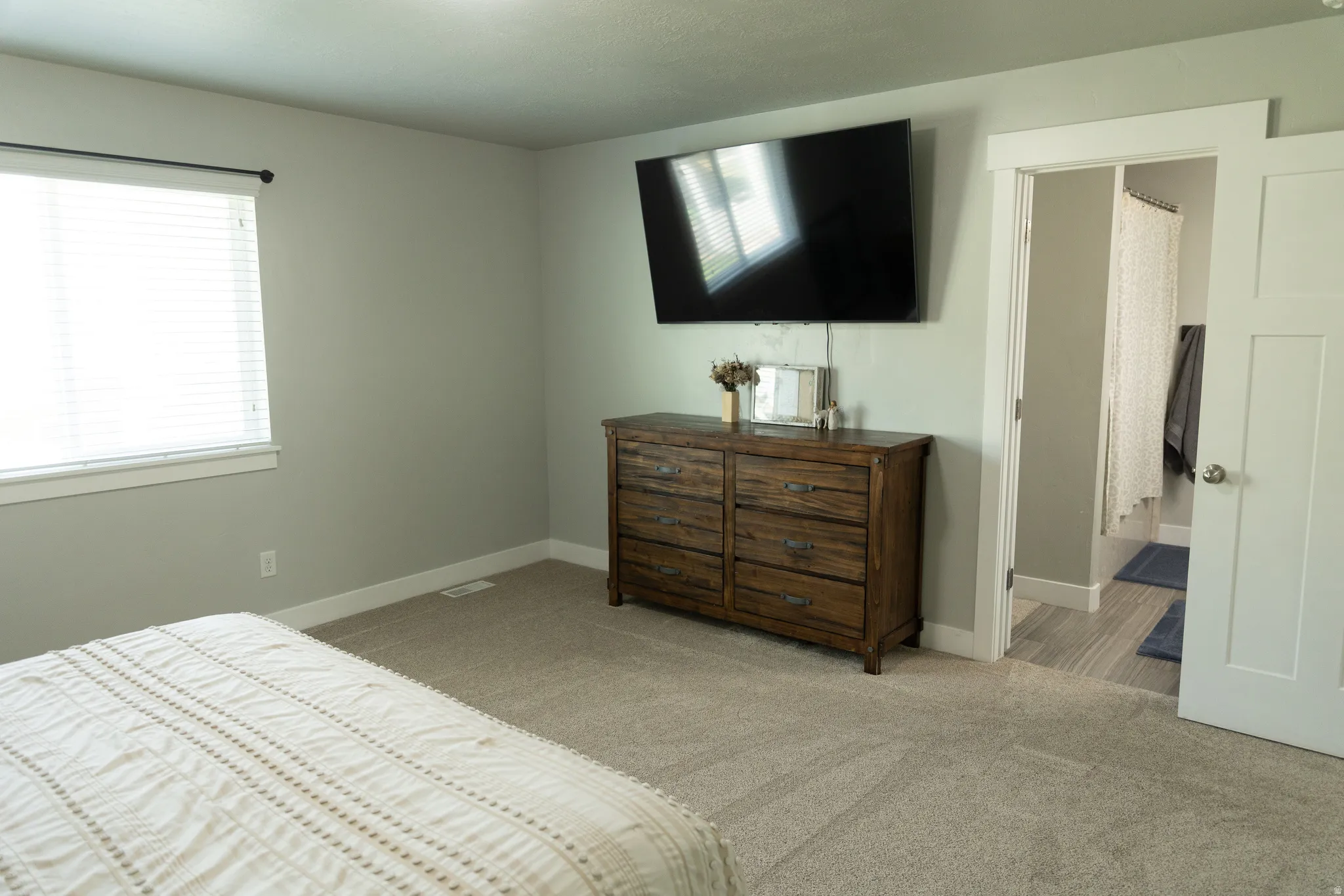 Wall-mounted television above a wood-finish dresser