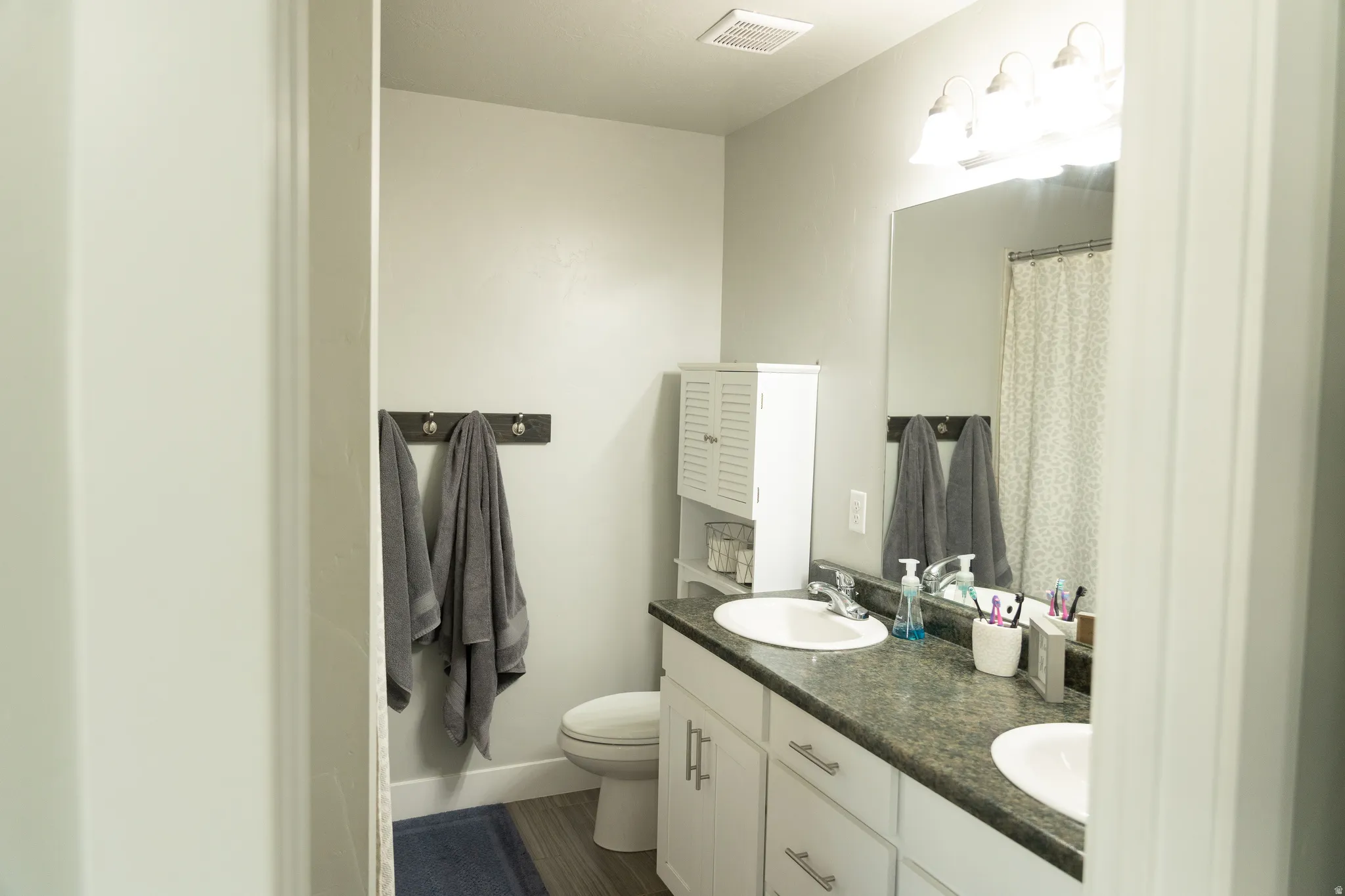Dual vanity with white cabinetry and dark countertops