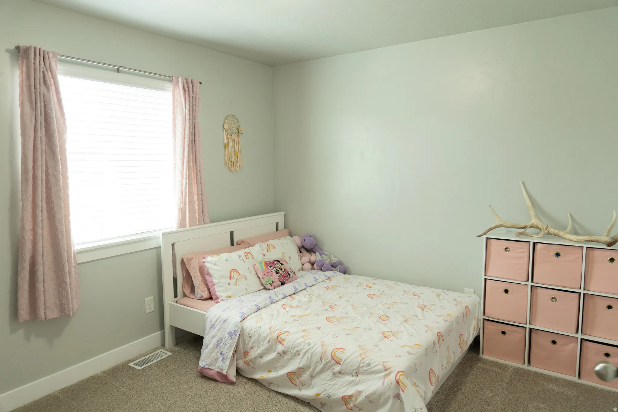 Neutral wall color, white window trim, white horizontal window blinds, carpeted flooring, and a white storage cubby unit