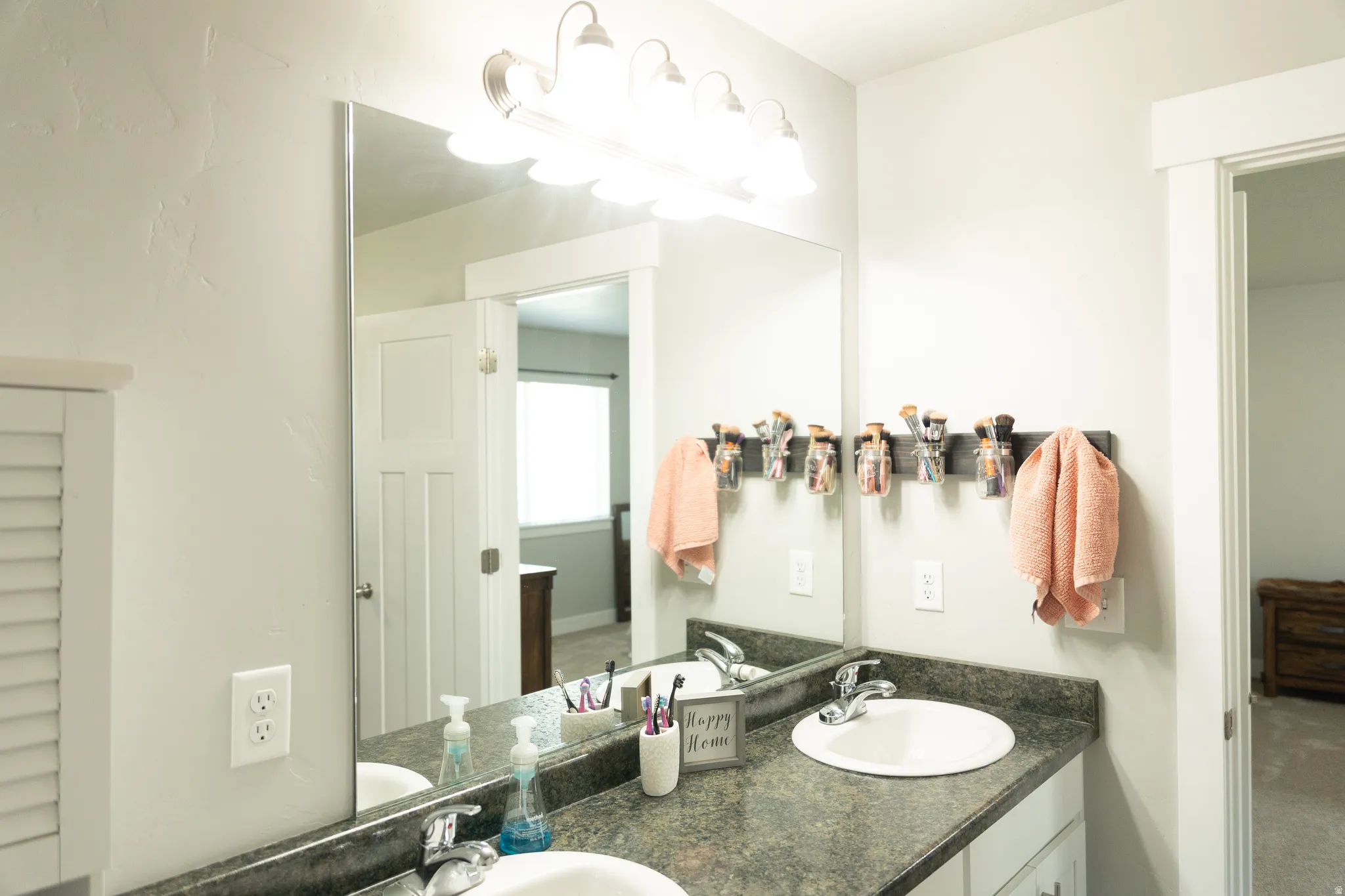 Dual vanity featuring white oval sinks, dark countertop, and brushed nickel fixtures