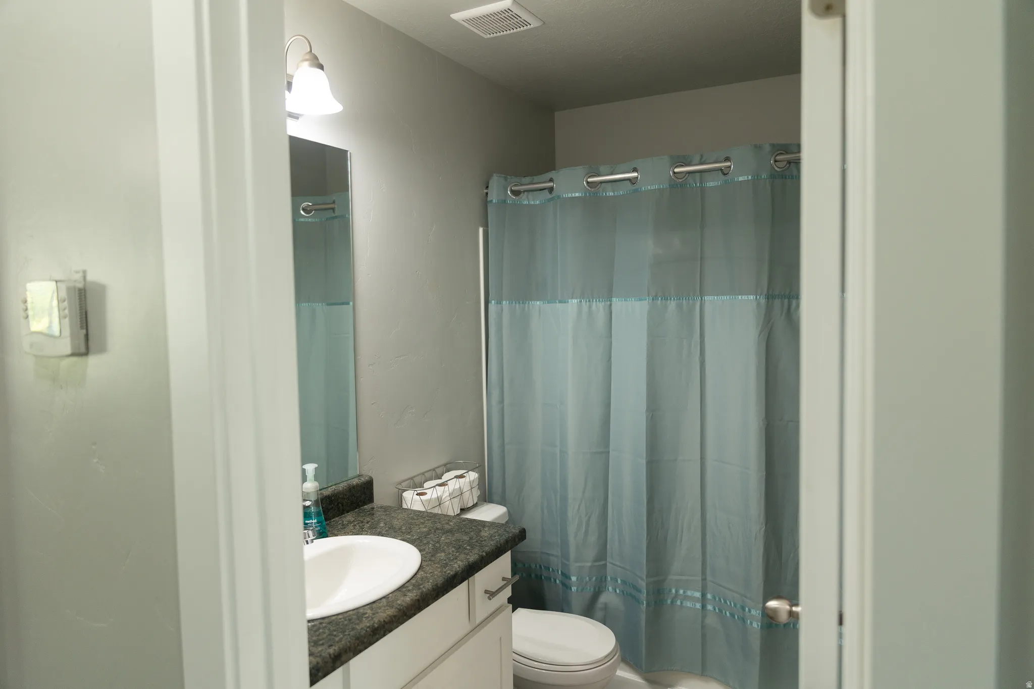 Bathroom featuring a vanity with an integrated sink, dark-toned countertop, and lower cabinetry