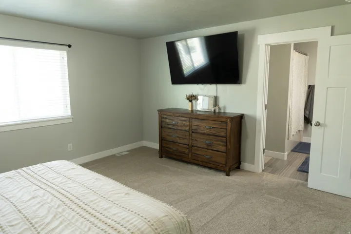 Wall-mounted television above a wood-finish dresser