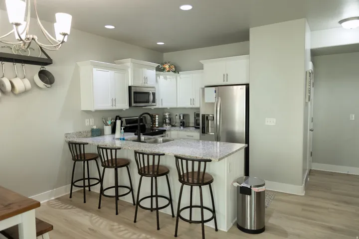 White cabinetry, stainless steel appliances, speckled countertops, recessed lighting, and wood-finish flooring