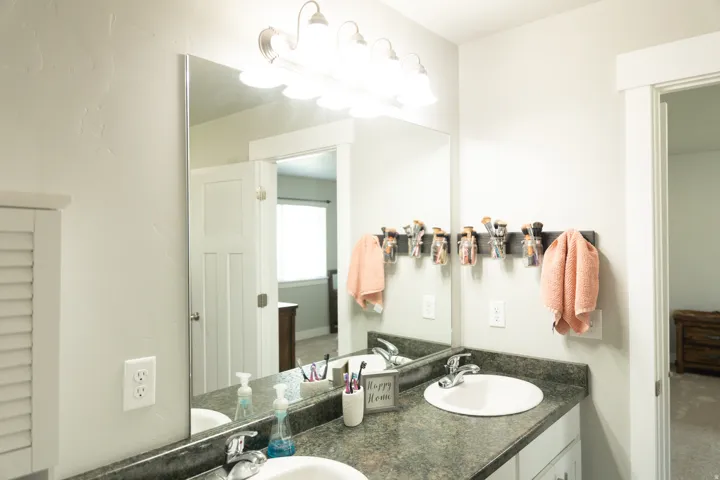 Dual vanity featuring white oval sinks, dark countertop, and brushed nickel fixtures