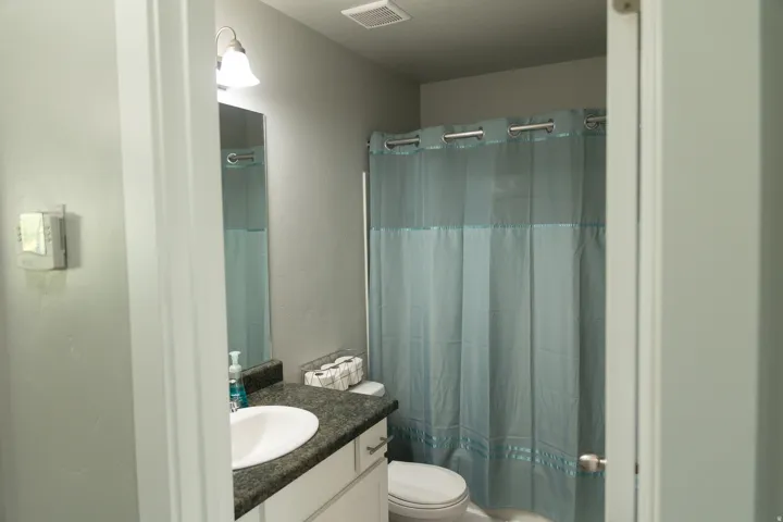 Bathroom featuring a vanity with an integrated sink, dark-toned countertop, and lower cabinetry