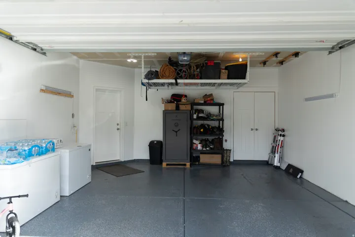 Epoxy-coated flooring, overhead storage racks, interior access door, recessed ceiling lighting, and built-in closet with bifold doors