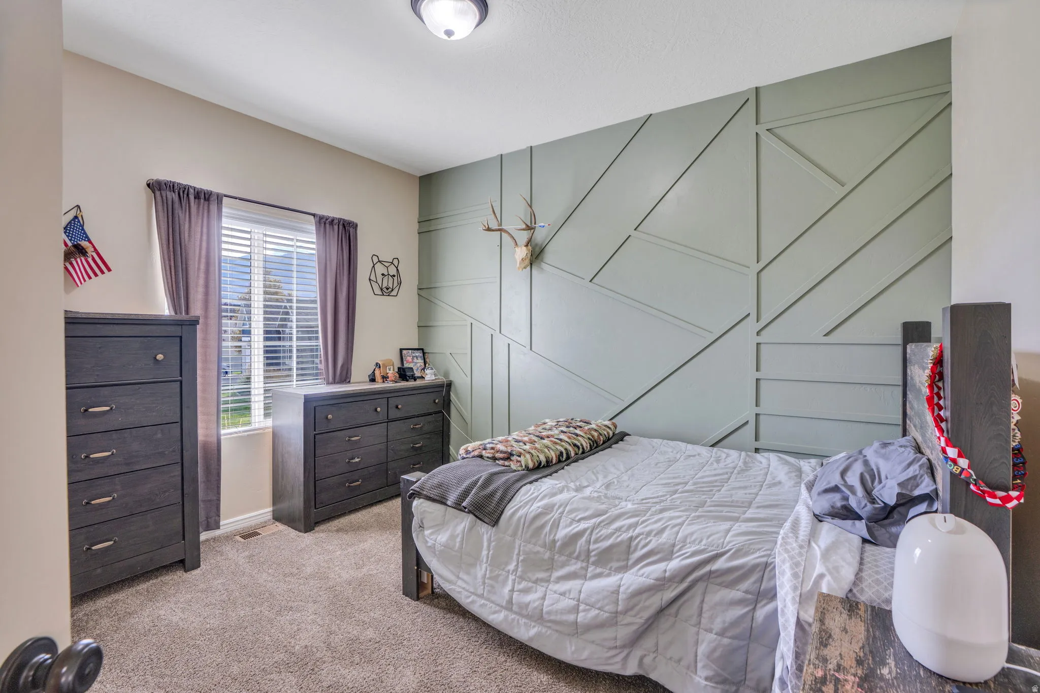 Accent wall with geometric paneling, window with blinds, and ceiling-mounted light fixture