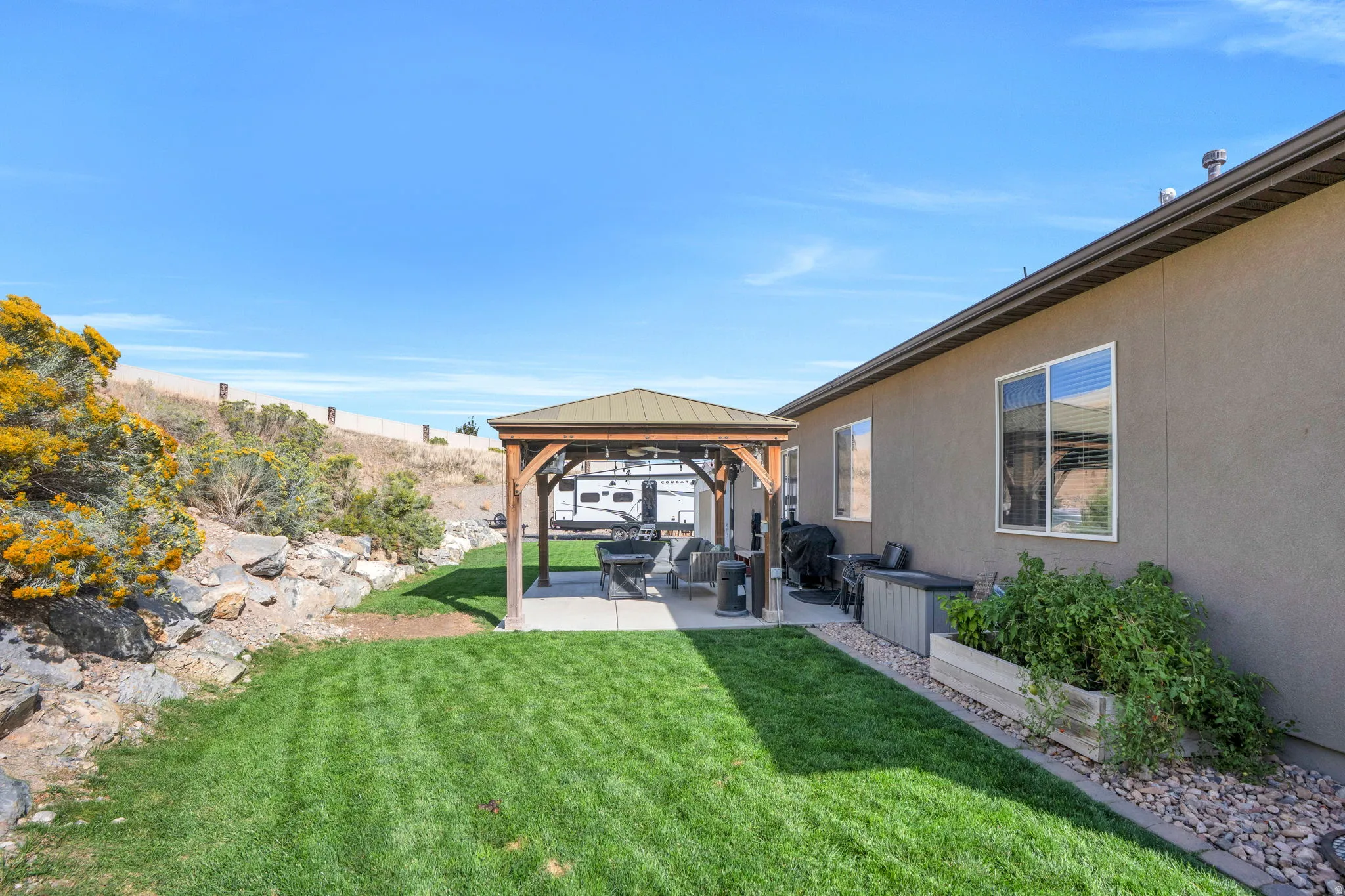 Manicured lawn with a wood-frame gazebo over a concrete patio