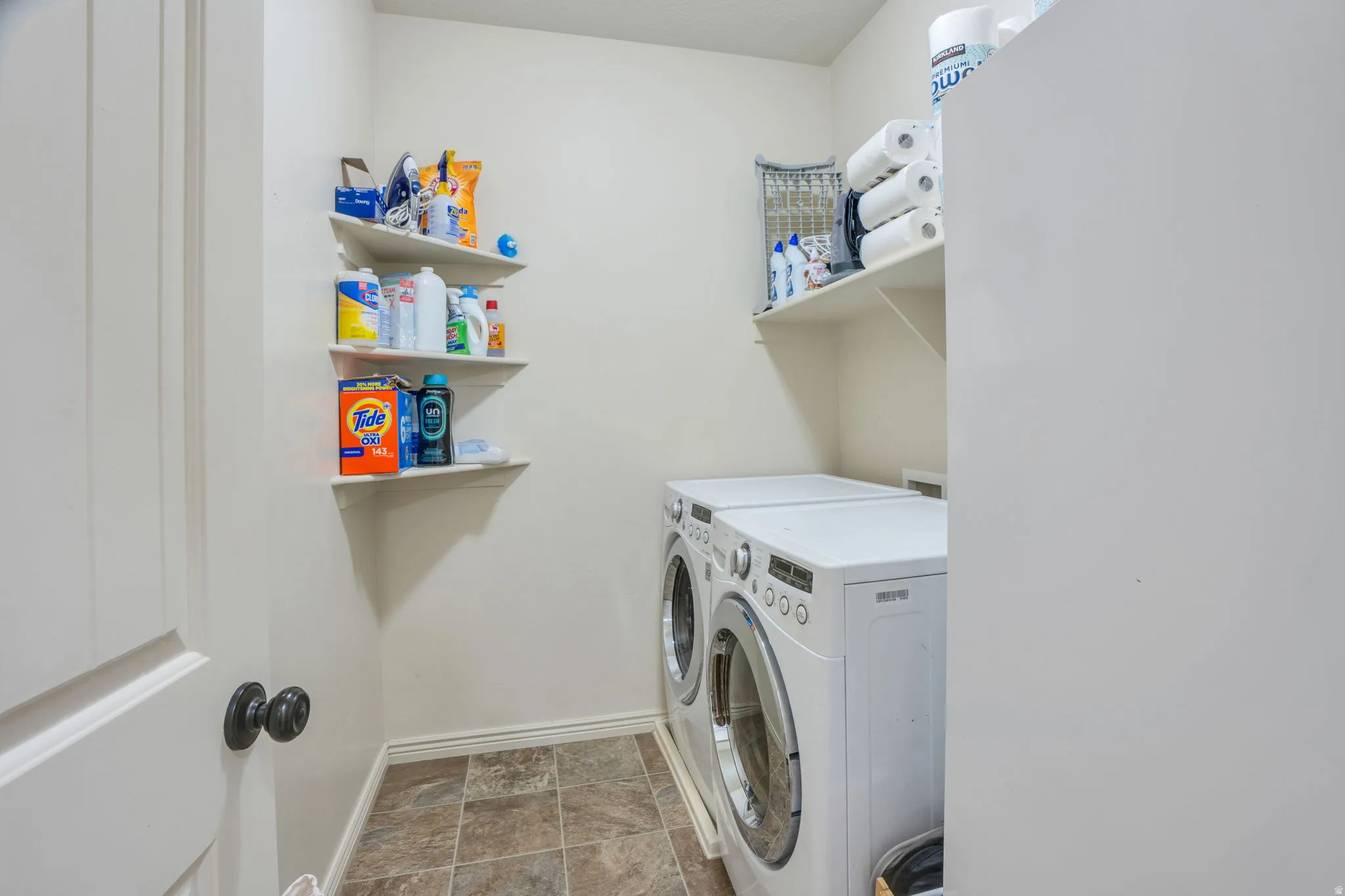 Laundry area with tiled flooring, white built-in shelving, and light-colored walls