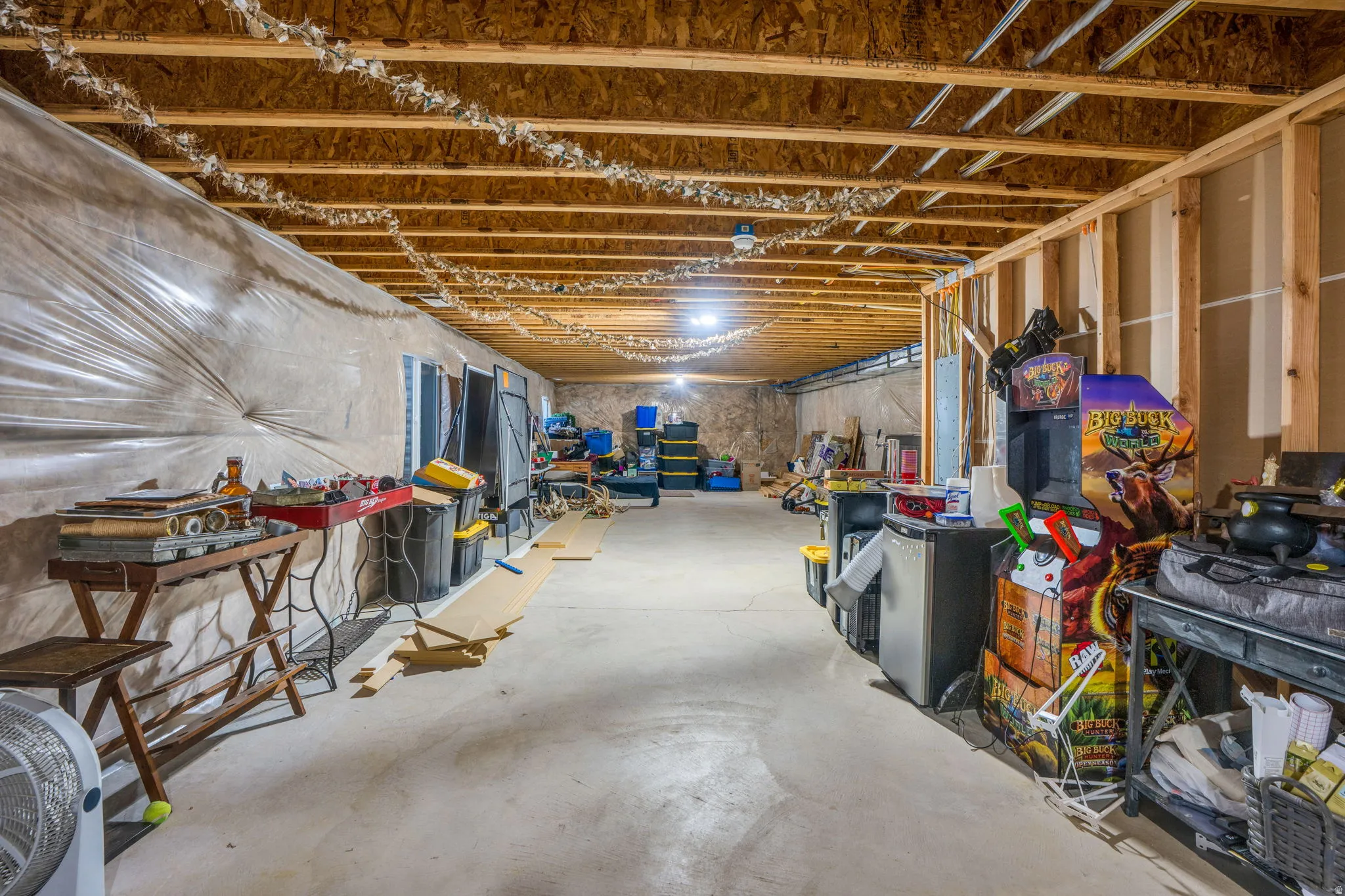 Unfinished basement space featuring exposed wood joists, concrete flooring, and partial wall framing