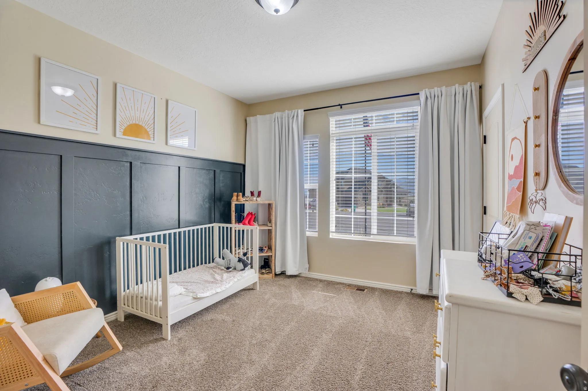 Wall paneling accent, dual windows, ceiling-mounted light fixture, and neutral carpeting