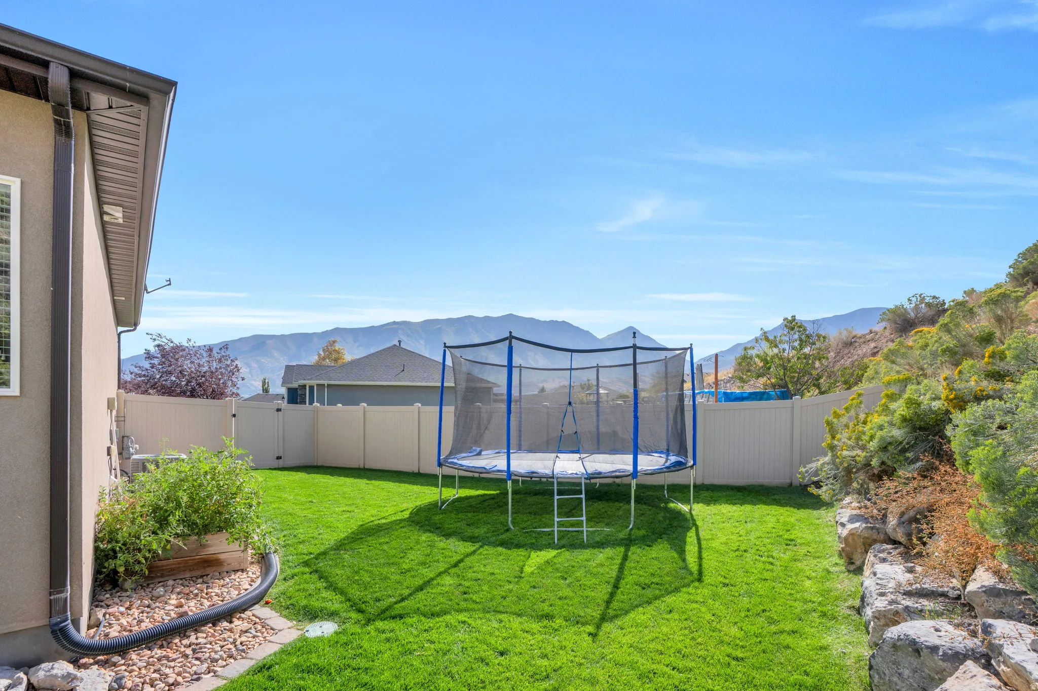Expansive green lawn with a privacy fence, landscaping, and distant mountain scenery