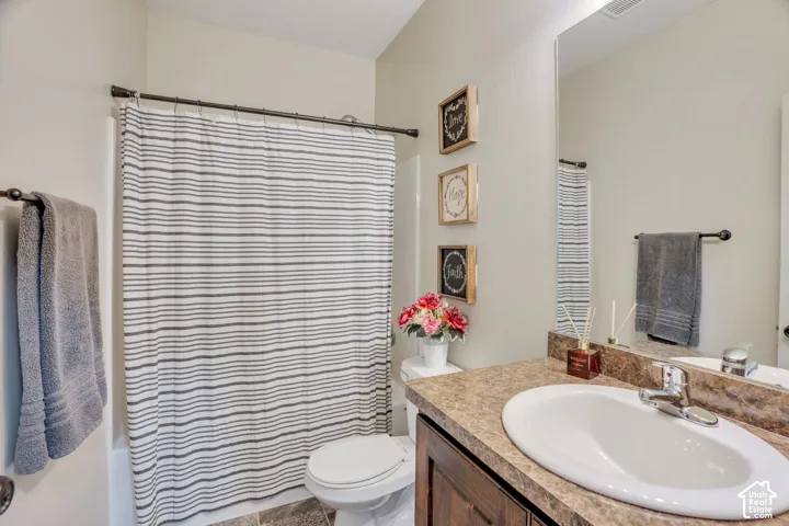 Full vanity mirror, integrated sink, wood-finish cabinetry, and a full bathtub with shower