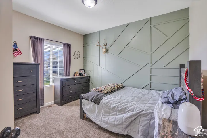 Accent wall with geometric paneling, window with blinds, and ceiling-mounted light fixture