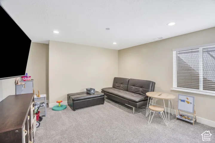 Recessed lighting, neutral wall tones, window with horizontal blinds, carpeted flooring, and a built-in media console