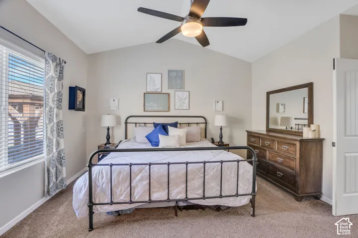 Vaulted ceiling with a ceiling fan, window with blinds, and carpeted flooring