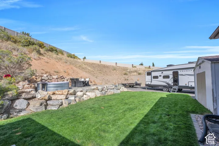 Expansive outdoor space featuring a manicured lawn, stone retaining walls, and a dedicated gravel area