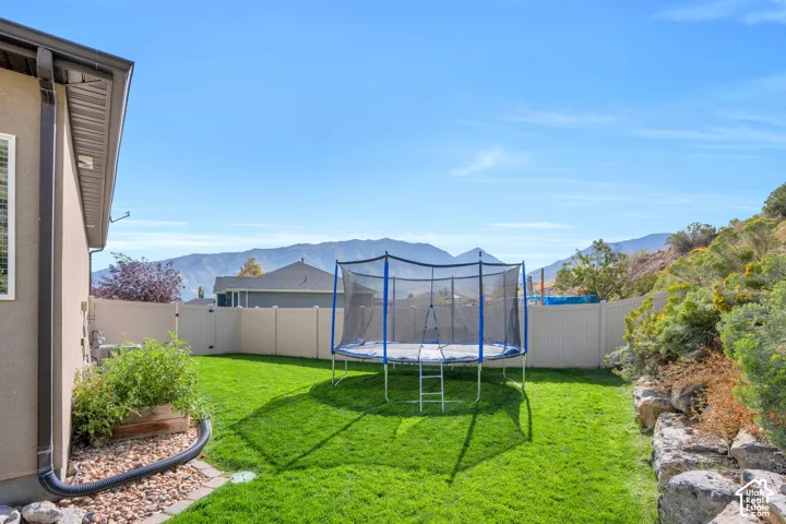 Expansive green lawn with a privacy fence, landscaping, and distant mountain scenery