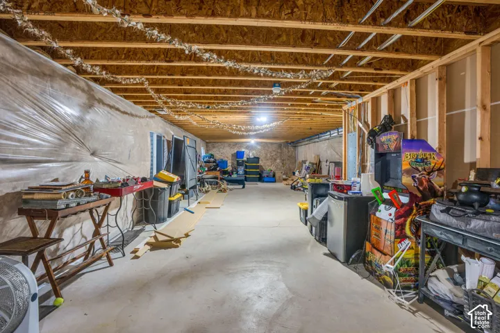Unfinished basement space featuring exposed wood joists, concrete flooring, and partial wall framing