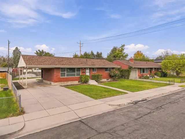 Brick exterior, attached carport, mature landscaping, paved driveway, and established sidewalks