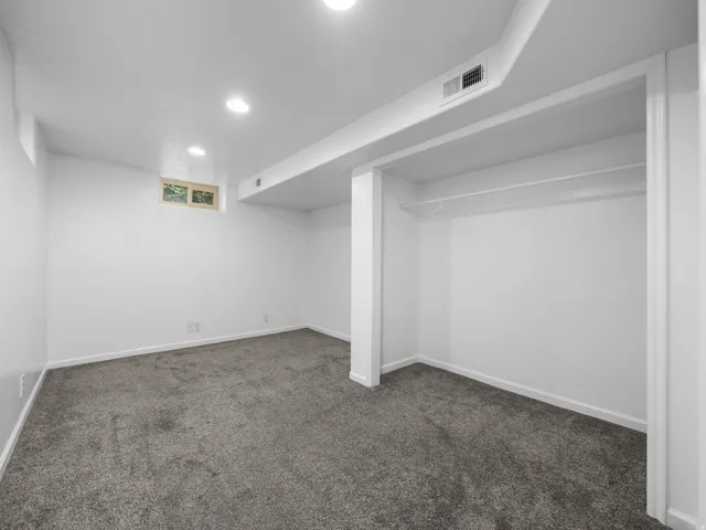 Recessed ceiling lighting, gray carpet flooring, egress window, white walls, and built-in closet rod