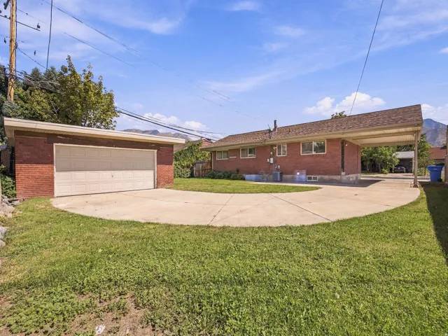 Brick exterior home with an attached carport, separate brick garage, and concrete driveway