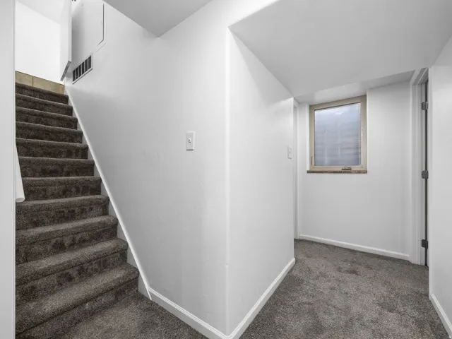 Carpeted staircase with white risers and an egress window with a stone sill