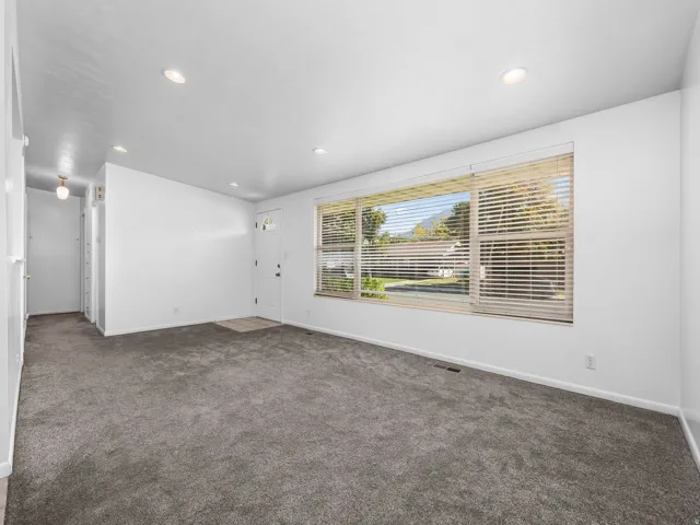 Spacious living area featuring neutral carpeting, a large picture window, and recessed lighting