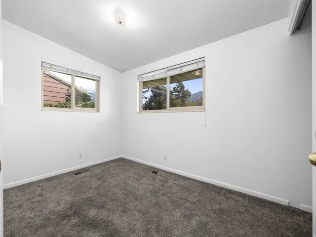 White walls, gray carpeting, and two windows