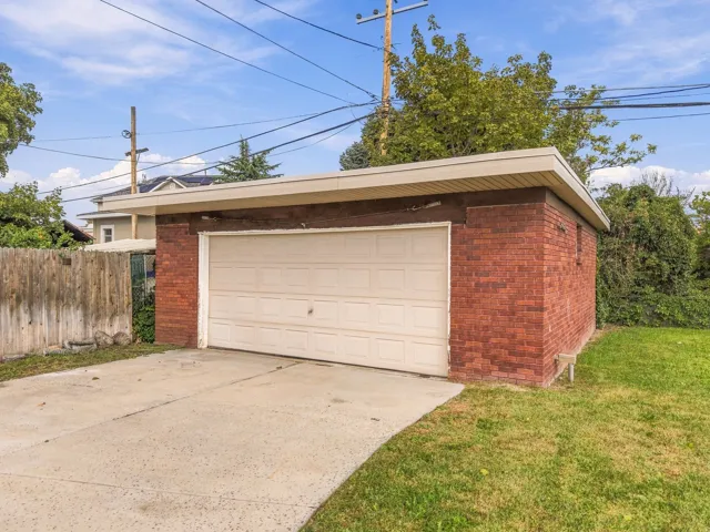 Brick detached garage with a paneled garage door and a concrete driveway