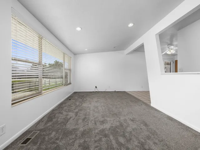 Recessed lighting illuminates the carpeted living area with expansive window placement