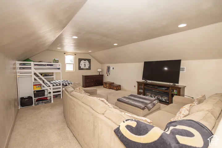 Carpeted room featuring a built-in electric fireplace, recessed lighting, a single window, and sloped ceilings