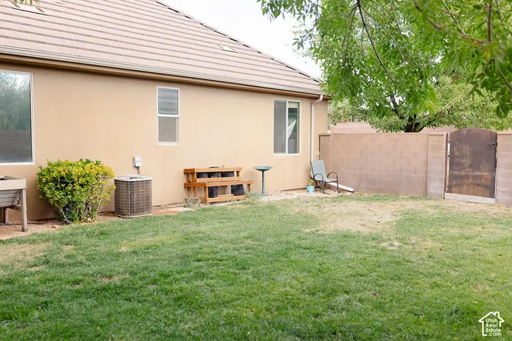 Backyard space featuring a block wall fence, a metal gate, and stucco exterior