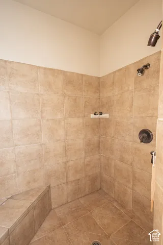 Tiled shower stall with a built-in bench, bronze-finish shower fixtures, and a tiled floor with a center drain
