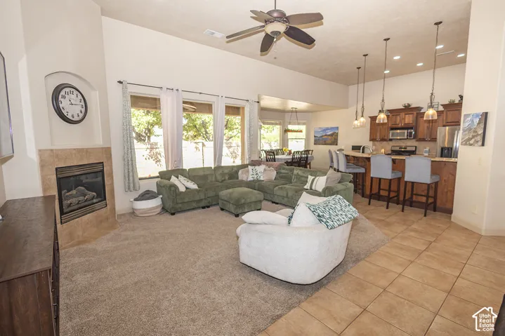 Vaulted ceilings, a tiled fireplace, large windows, recessed lighting, and a kitchen with stainless steel appliances