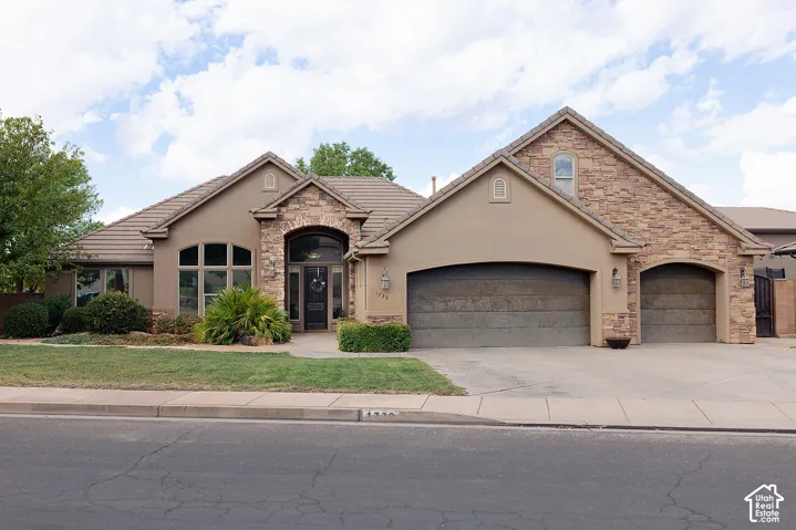 Stucco exterior with stone accents, arched entryway, and a tiled roof