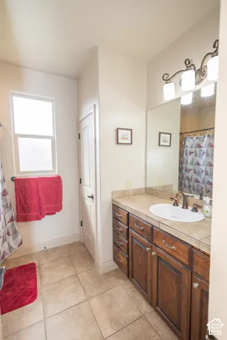 Wood-finish vanity with an integrated sink, tile countertop, and mounted mirror
