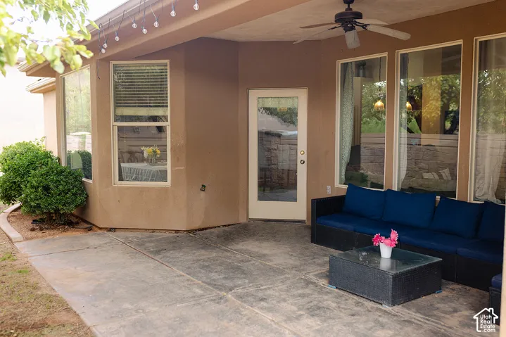 Covered patio featuring a ceiling fan, multiple large windows, and a glass-paneled door