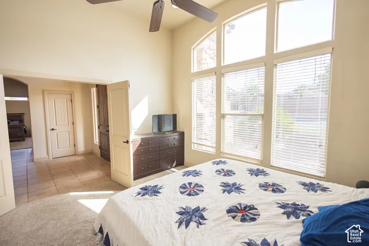 Vaulted ceiling with a ceiling fan, arched transom windows, and multiple large windows