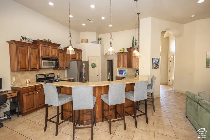 Kitchen featuring wood cabinetry, stainless steel appliances, a breakfast bar, recessed lighting, and tile flooring
