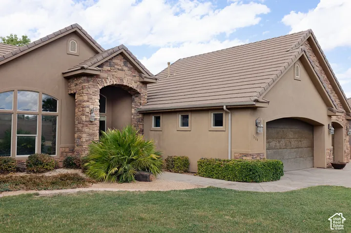 Stucco exterior with stone accents, arched entry, arched garage door, and tile roofing