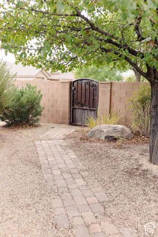 Paver pathway leading to a decorative wooden gate set within a block wall