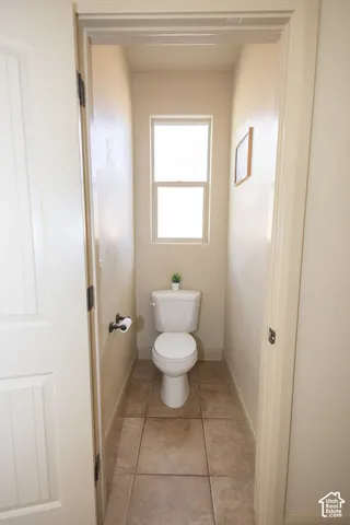Recessed powder room with a single window, ceramic tile flooring, and a white toilet