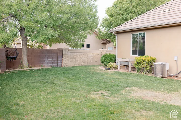 Grassed backyard with mature trees, stucco exterior, and tile roof