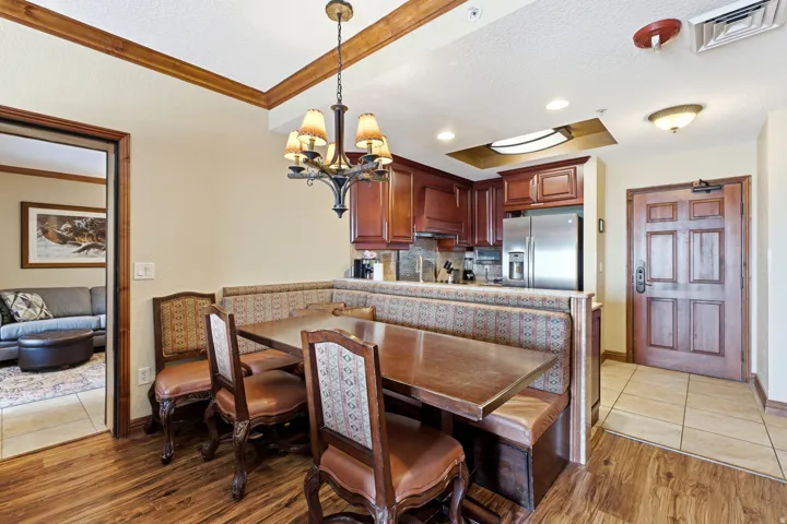 Wood-finish flooring, built-in banquette seating, stainless steel refrigerator, wood cabinetry, and crown molding accents