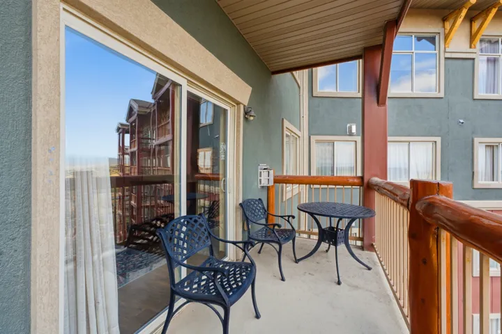Outdoor balcony featuring a sliding glass door, concrete flooring, and log-style railings